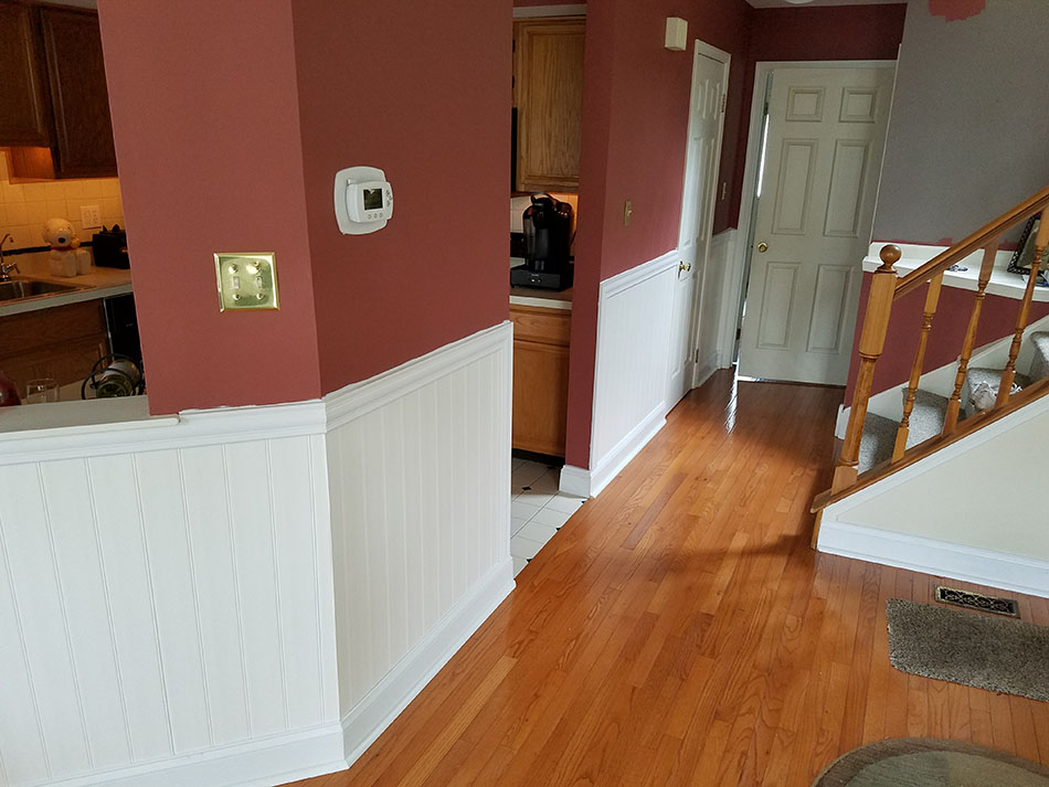 brown hardwood flooring with glossy look next to a kitchen area and staircase