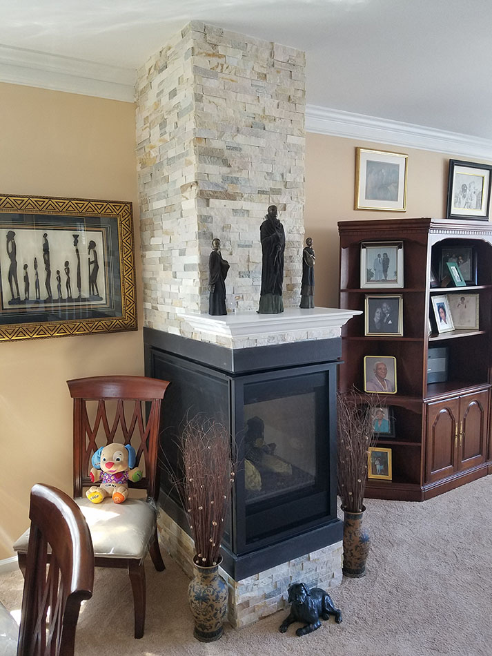 living room area with a small black fire place attached to a stone brick column