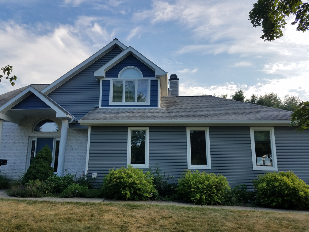 large blue home , two story, with front yard in view, bushes