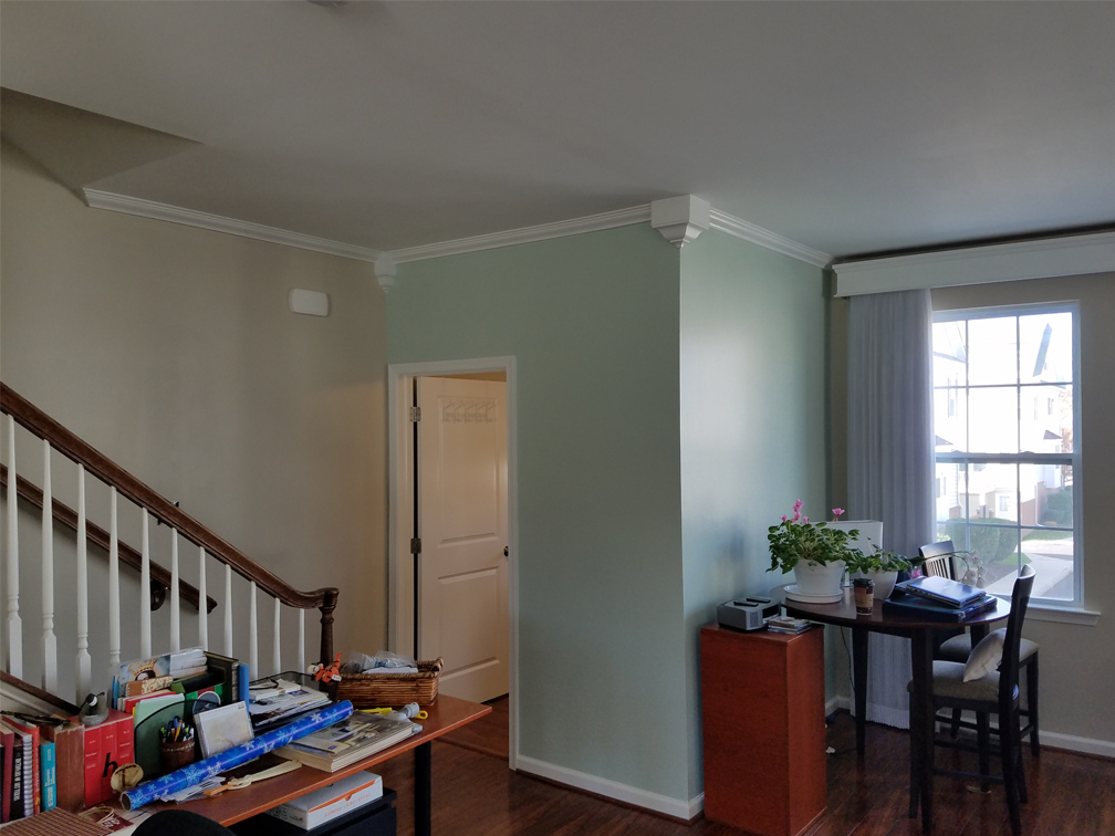 small living room are a with light green walls, staircase, some clutter