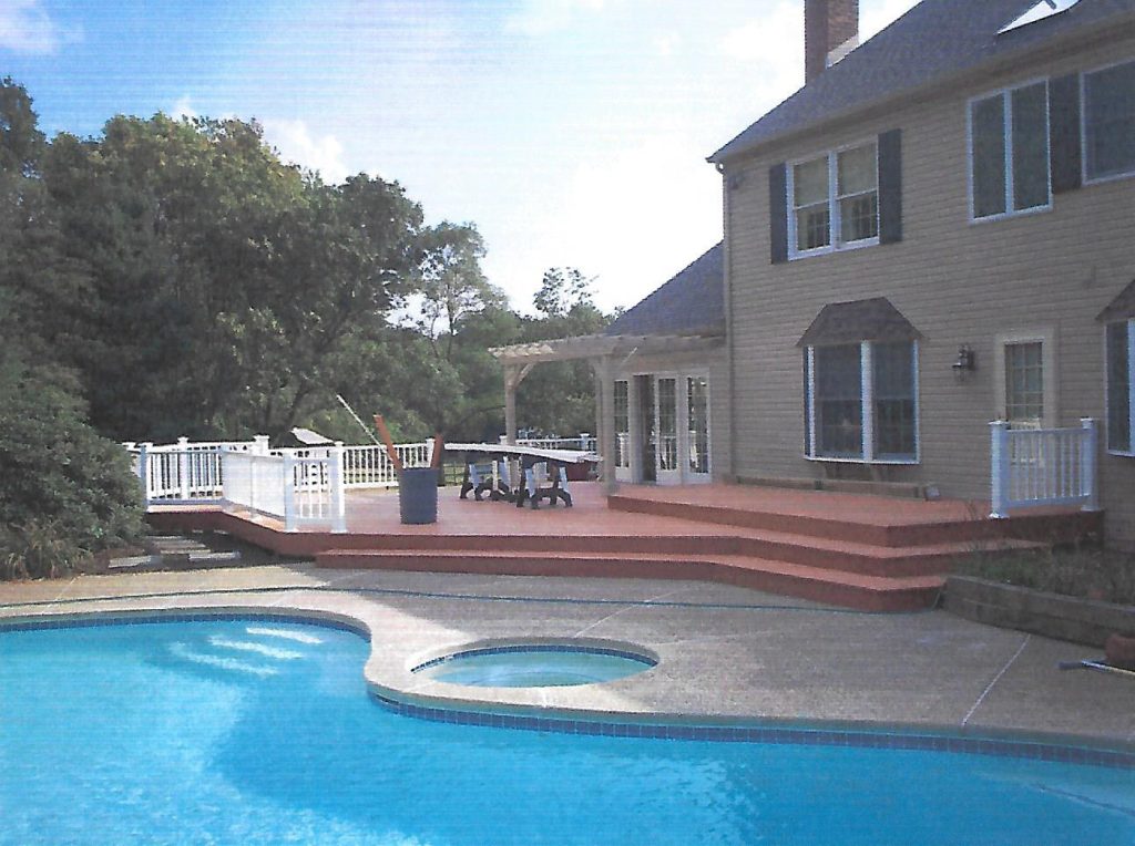backyard area of a home with an in-ground pool, stone walkway, deck area